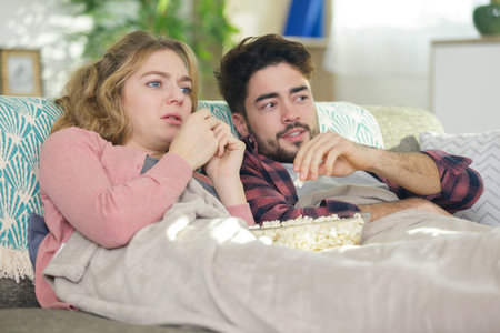 emotional couple snuggled under a blanket watching a movie