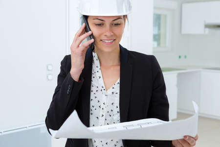 beatiful woman engineer with plans papers on building siteの写真素材