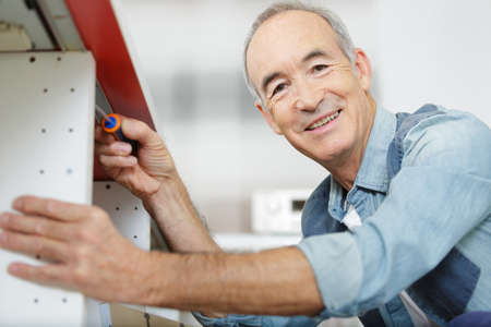 a senior man assembles furnitureの写真素材