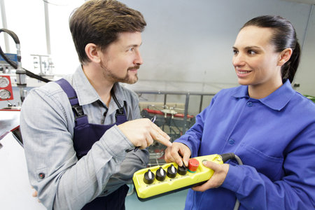 male and female workers looking at factory machinery