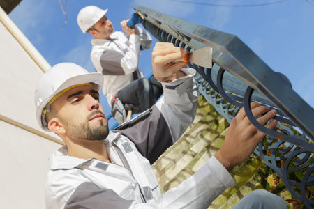 painters preparing surface of railings to be repainted