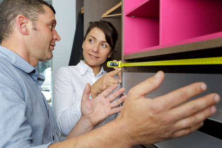 couple measuring cupboard in furniture storeの写真素材