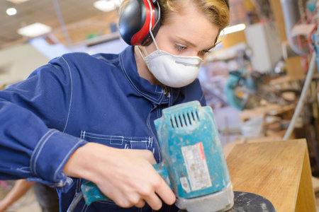 woman carpenter sanding wood plank