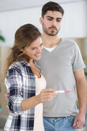 worried man checking pregnancy test with his excited wifeの写真素材