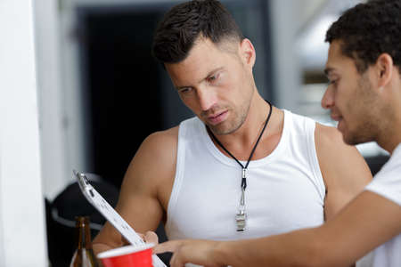 sports coach with clipboard talking to young sportsmanの写真素材