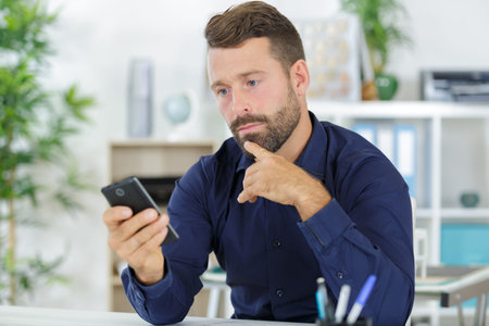 man with mobile phone and laptop in office