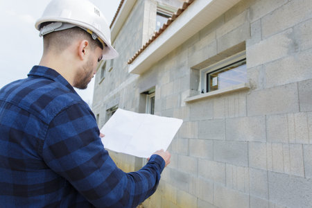 Worker checking wall of construction site