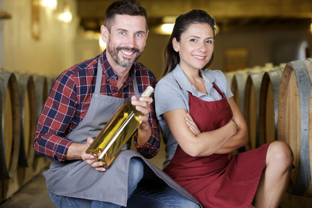 Handsome couple of sommelier in apron looking at camera