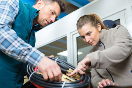 Male and female mechanics looking at new jump-leads