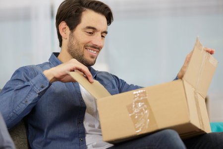 Portrait of man opening a parcel at home