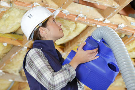 lady fitting ventilation hose into roof spaceの写真素材
