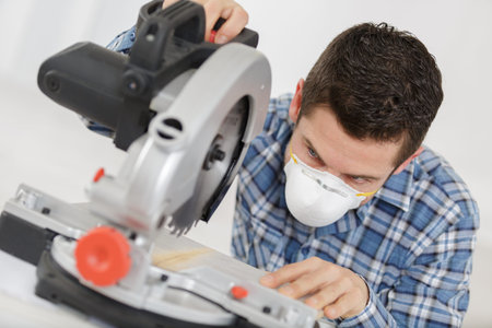 man wearing dust mask using circular saw