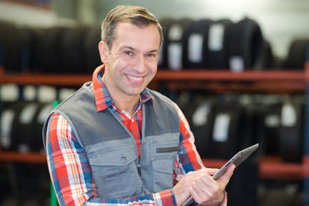 happy mechanic uses a tablet in garageの写真素材