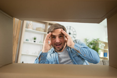 man smiling unpacking opening carton box and looking inside