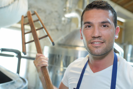 portrait of worker holding wooden mixing tool