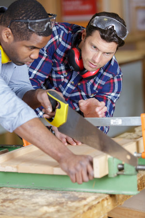 men sawing a wooden plank
