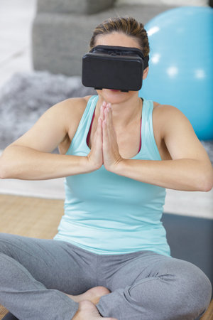 young woman doing yoga with virtual reality glasses