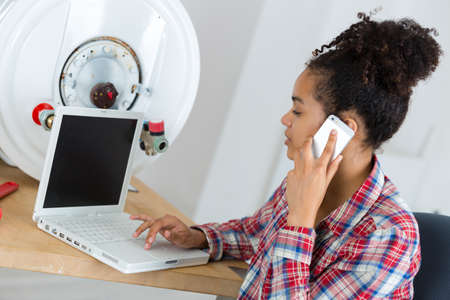 female plumber working on central heating boilerの写真素材