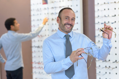 man choosing glasses in optics store
