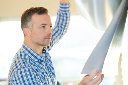 man inspecting very thin aluminum sheetの写真素材