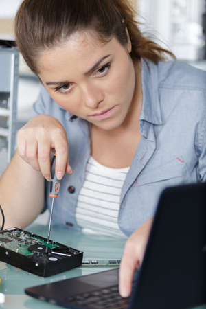 a woman fixing a laptopの写真素材