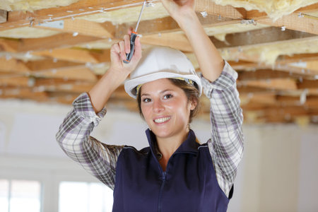 female electrician installing lights in ceiling