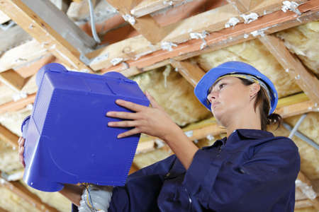 female builder during ventilation pipes installationの写真素材
