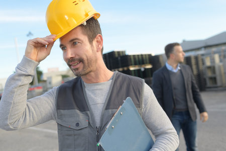 worker putting his hardhat and holding clipboard