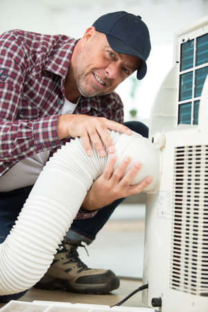 mature male worker carefully installing new acの写真素材