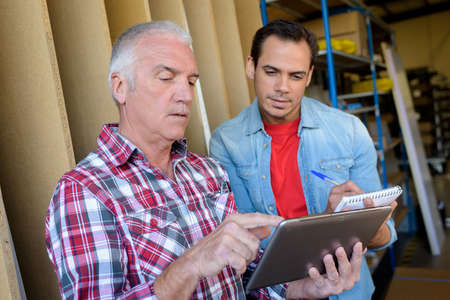 two workers at an industrial plant with a tabletの写真素材
