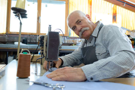 worker posing next to sewing machineの写真素材