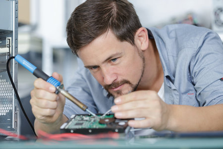 a male worker is soldering cable