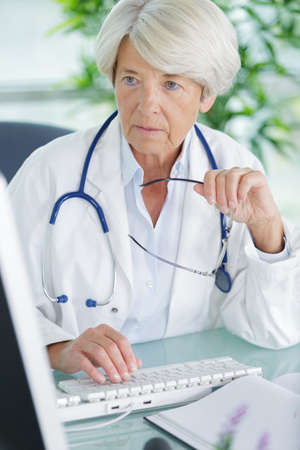portrait of senior doctor sitting in medical officeの写真素材