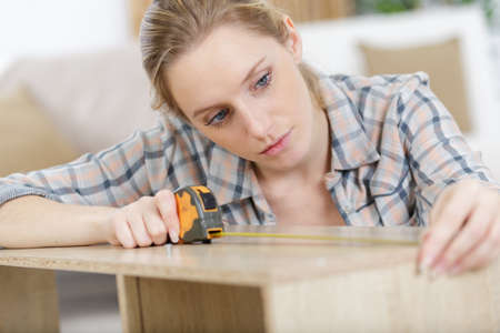 a female carpenter measuring woodの写真素材
