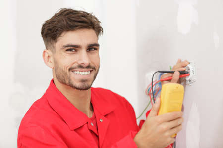 a happy electrician installs socketの写真素材