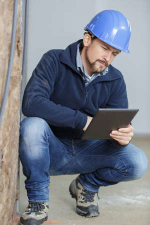 tradesman crouching and looking at a tabletの写真素材