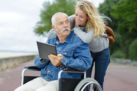 daughter and old man on wheelchair with tabletの写真素材