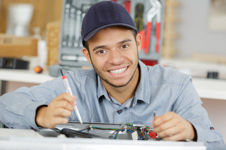 Young serviceman repairing washing machine