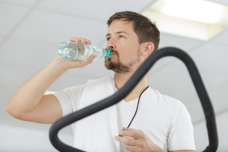 serious man drinking water in the gym