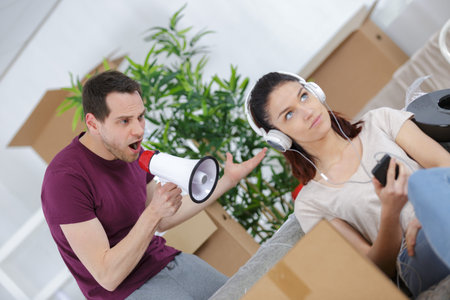 Young man using loudspeaker to his  lazy girlfriend