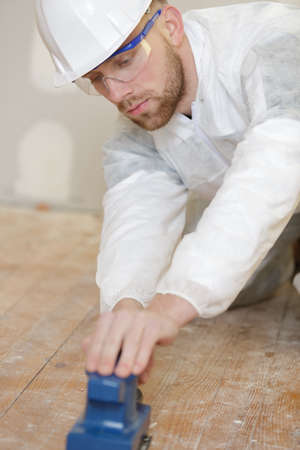 male tradesman sanding wooden floorの写真素材