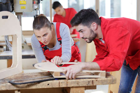 Woman and man cutting wood with grinder during her apprenticeshipの写真素材