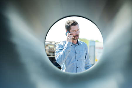 Male manager on the phone through a pipeの写真素材