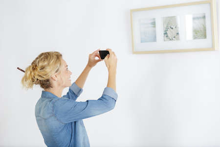 Young woman takes picture of paintingsの写真素材