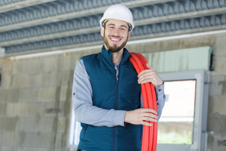 Plumber with reel of red pipe over his shoulderの写真素材