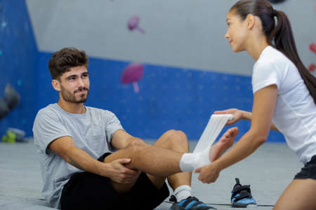 woman wrapping bandage on man who had accident on sportsの写真素材