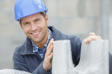 happy male builder holding a cement block