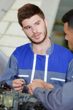 apprentice mechanic in auto shop working on car engineの写真素材