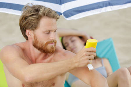 man holding sunscreen bottle in handの写真素材