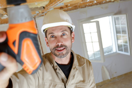 portrait of a worker drilling ceiling